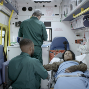 In the back of an ambulance, two paramedics tend to a patient who has recently experienced a miscarriage